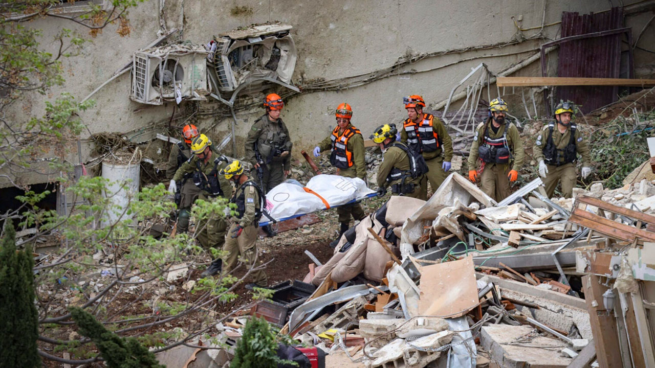 Israeli rescue forces recover bodies at the scene where a missile fired from Iran struck a building in Haifa, April 6, 2026. (David Cohen/Flash90)