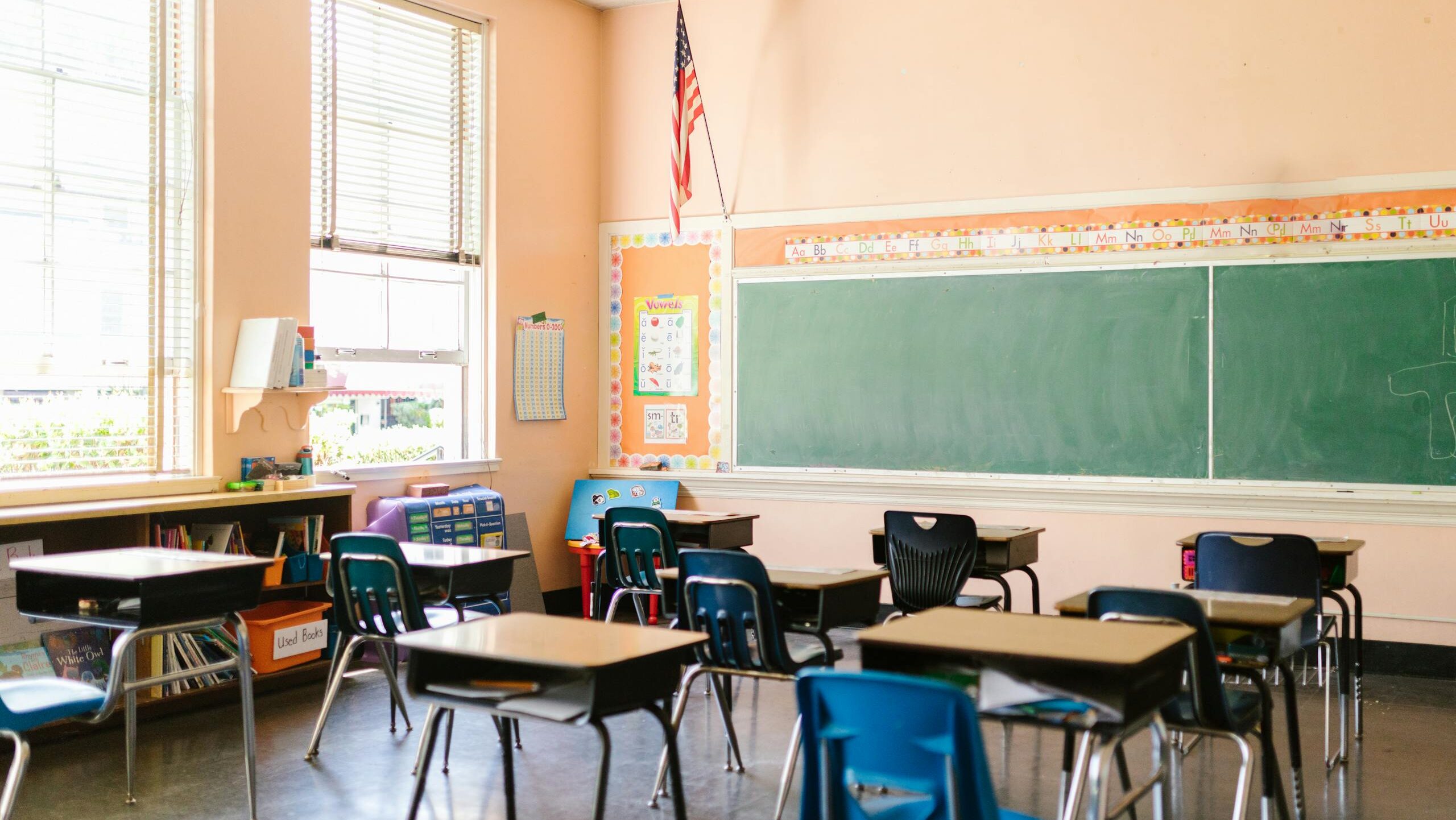 An inviting, sunlit classroom with empty desks and an American flag, ready for students.