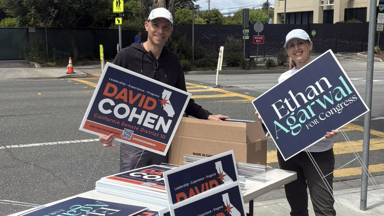 Two people hand out yard signs