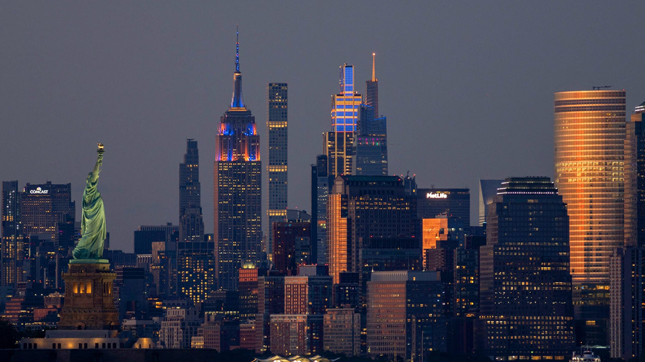 The Empire State Building, JPMorgan Chase Building, and One Vanderbilt in New York City are illuminated in the colors of the New York Knicks during Game 5 of the NBA Finals on June 13, 2026, as seen from Bayonne, New Jersey. (Gary Hershorn/Getty Images)