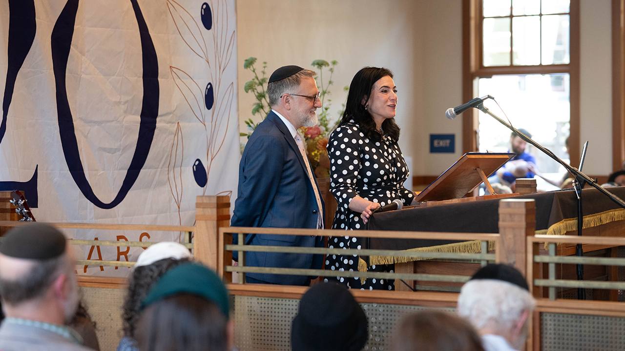 Rabbi Yonatan Cohen (left) and his wife Frayda Gonshor Cohen speak at a gala at modern orthodox synagogue Congregation Beth Israel in Berkeley, June 14, 2026. (Hagit Caspi/Courtesy Congregation Beth Israel)
