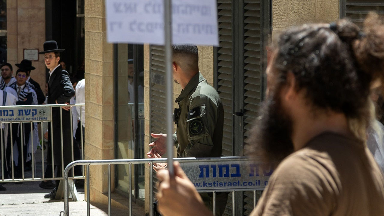 Haredi protesters and secular counter-protesters are separated by police outside Cafe Basimta in Jerusalem, July 18, 2026. (Theia Chatelle)