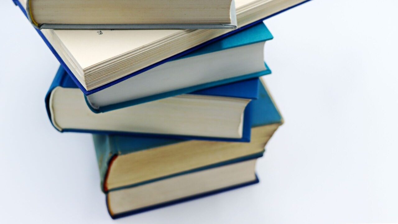 A pile of books with blue covers on a white background, symbolizing education and knowledge.